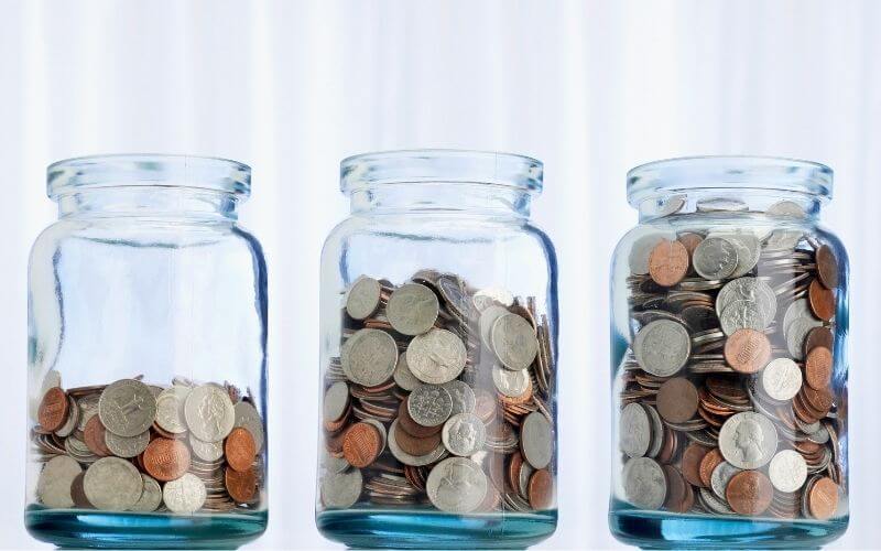 3 glass jars full of coins for how to be frugal